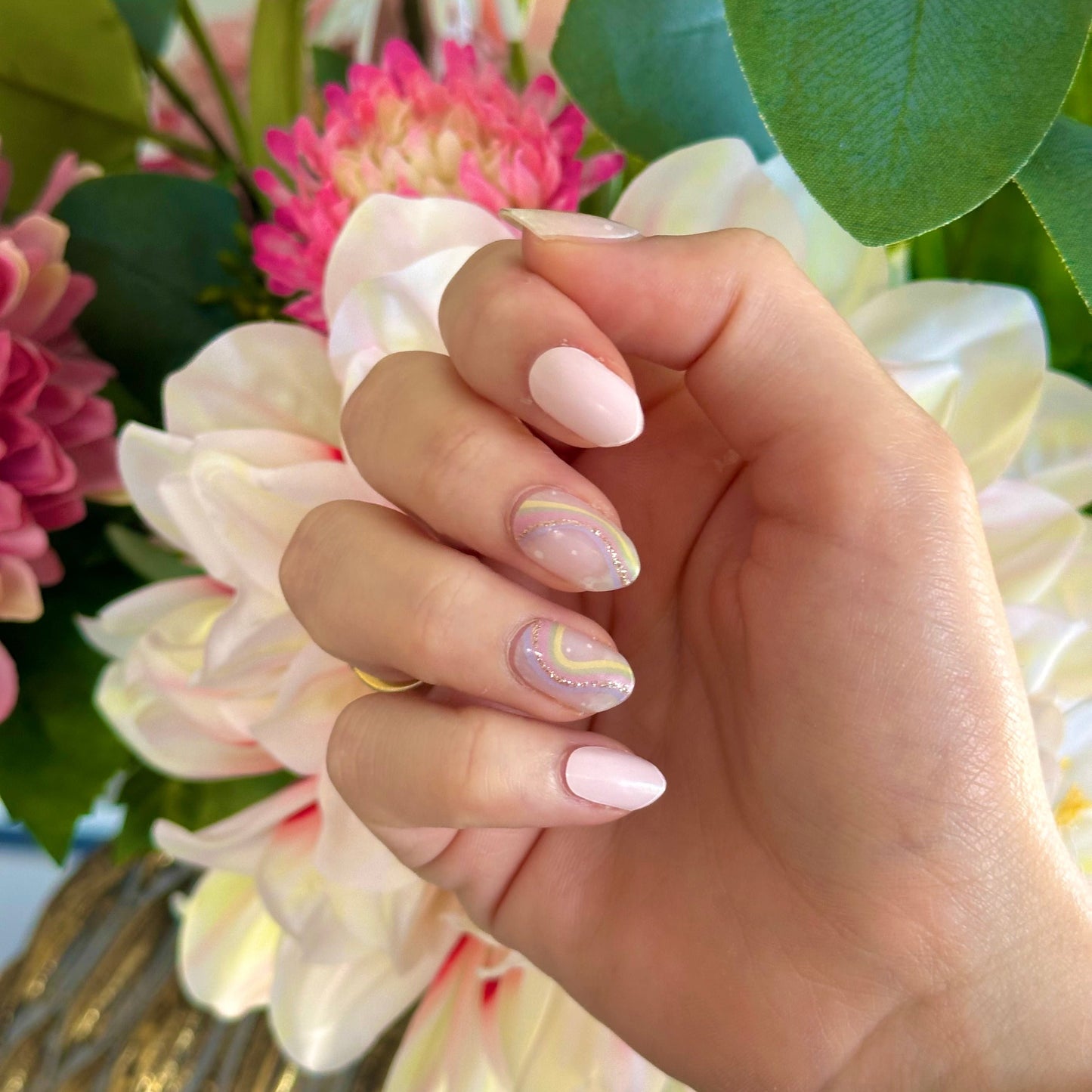 Gellakstickers met op een paar nagels effen roze en op andere nagels semi-transparante basis met zacht neutrale kleur regenboog en subtiele glitterboog 