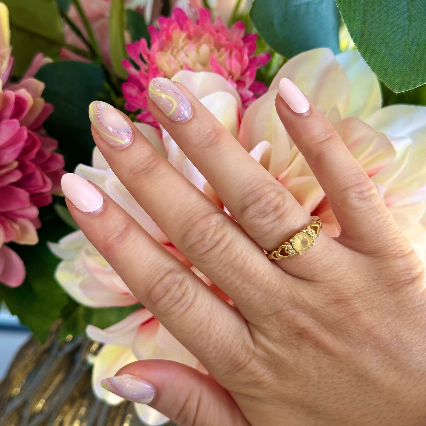Gellakstickers met op een paar nagels effen roze en op andere nagels semi-transparante basis met zacht neutrale kleur regenboog en subtiele glitterboog 