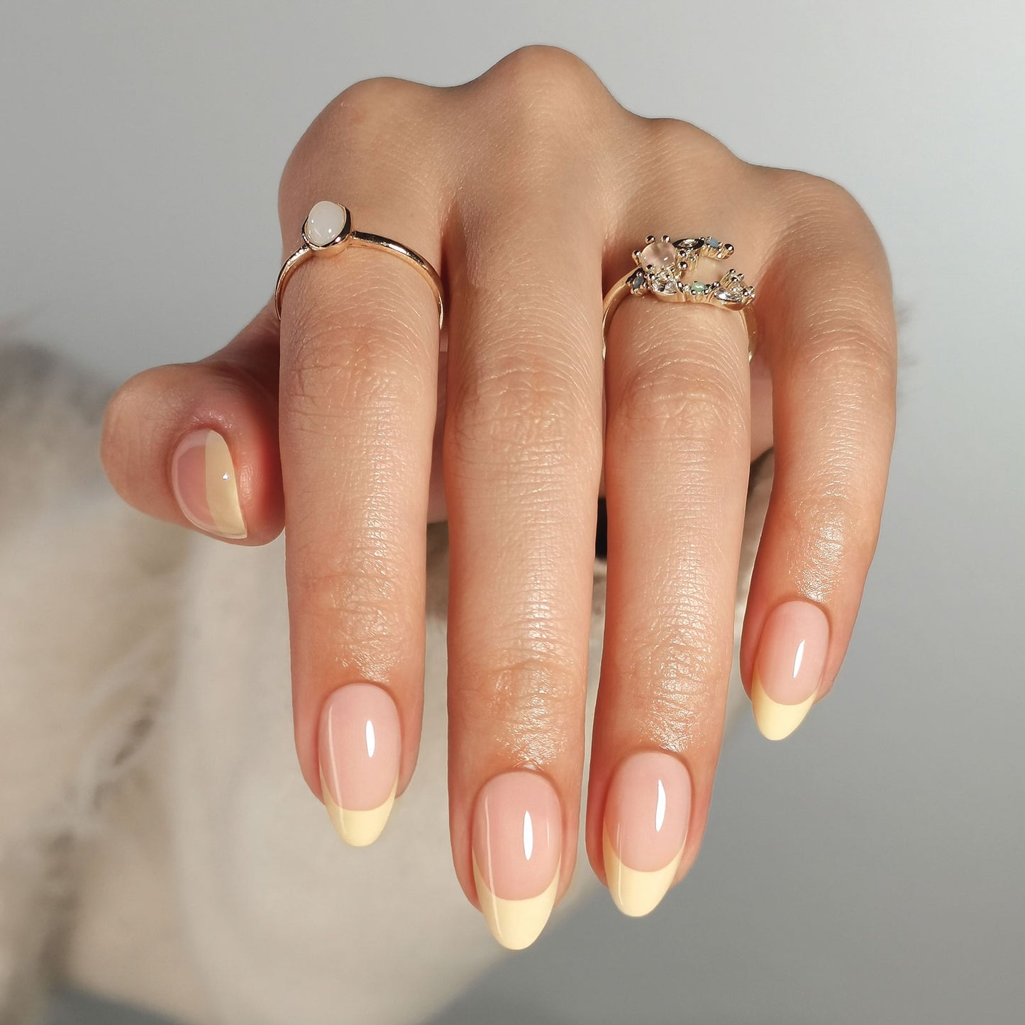 Butter yellow French press-on nagels in almond vorm met een natuurlijke nude basis en zachte botergele French tip