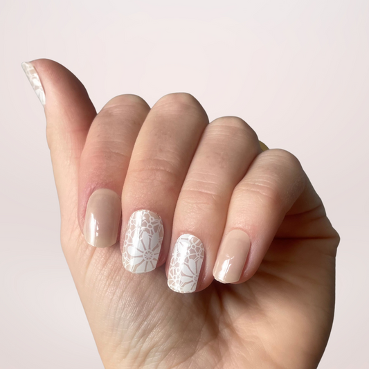 Een prachtige nude kleur met op een paar nagels nail art met witte bloemen in een 'lace' patroon. 