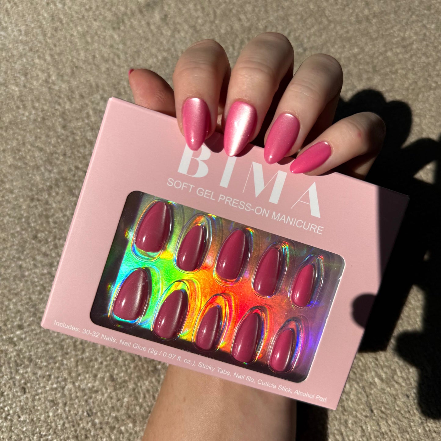 Roze almond cat-eye press-on nagels met de verpakking in de hand