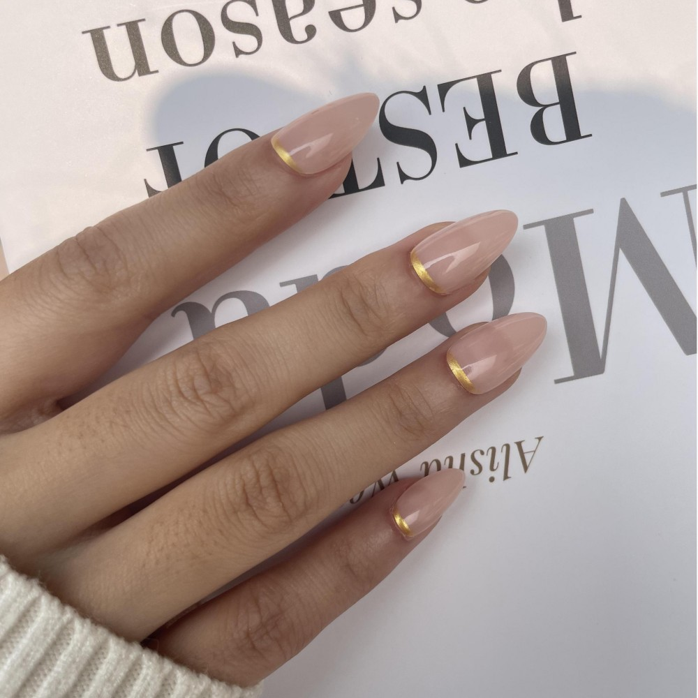 almond press-on nagels, een nude basis met onderaan een gouden lijn detail